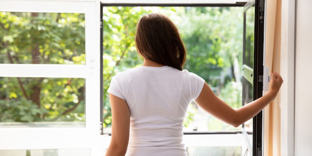 Side View Of A Woman Looking Through Window At Home
